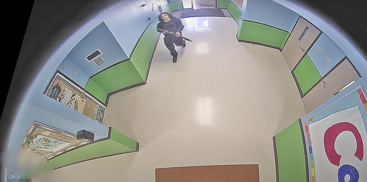 AP : A gunman carrying rifle and walks down the school hallway hallway 